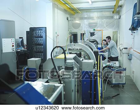 Stock Image - Scientists with particle accelerator. Fotosearch