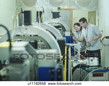 Stock Photo - Scientists with particle accelerator. Fotosearch