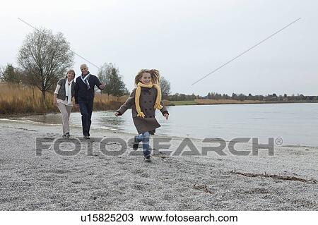 Stock Image - Senior couple and girl by lake. Fotosearch