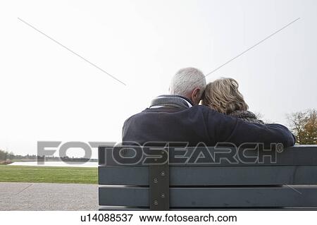 Senior couple sitting on bench in park View Large Photo Image Stock Photo - Senior couple sitting on bench in park. Fotosearch