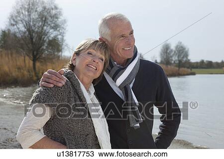 Stock Image - Senior couple walking by lake. Fotosearch
