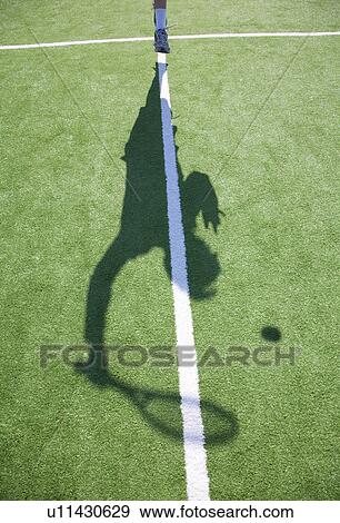 Stock Photo - Shadow of figure serving tennis ball. Fotosearch