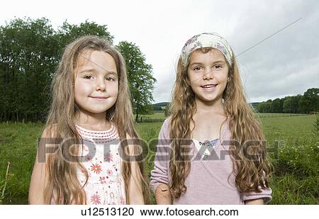 Sisters smiling in a field View Large Photo Image Stock Image - Sisters smiling in a field. Fotosearch