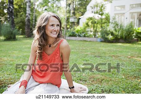 Smiling woman sitting in garden View Large Photo Image Stock Image - Smiling woman sitting in garden. Fotosearch