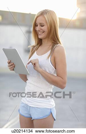 Picture - Smiling Women with ipad in sunset. Fotosearch