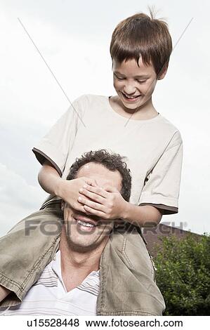 Stock Photo - Son cover's father's eyes. Fotosearch