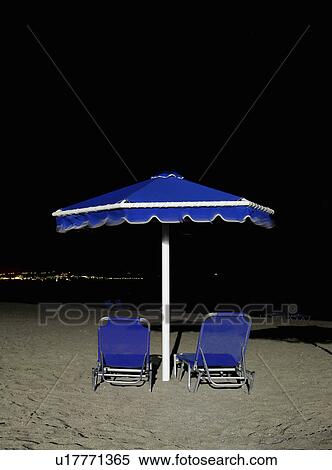 Stock Photography - Sunloungers and parasol at night. Fotosearch