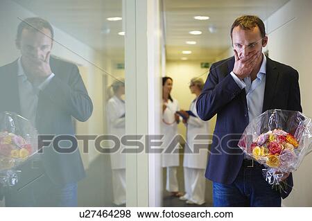 Stock Photo - Surprised man with flowers at hospital. Fotosearch