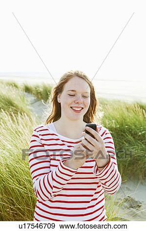 Stock Photo - Teenager texting on phone at beach. Fotosearch