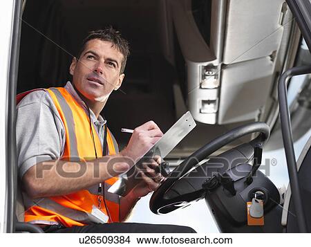 Truck driver makes notes in truck cab View Large Photo Image Picture - Truck driver makes notes in truck cab. Fotosearch