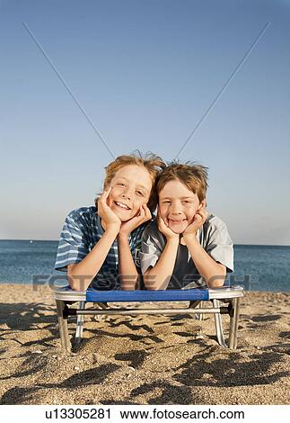 Two boys (7-9) lying on sunlounger View Large Photo Image Stock Image - Two boys (7-9) lying on sunlounger. Fotosearch