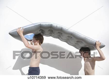 Stock Photo - Two boys carrying an inflatable lilo. Fotosearch