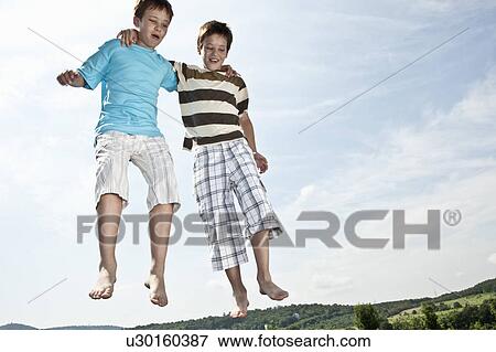 Two boys jumping on trampoline View Large Photo Image Stock Photo - Two boys jumping on trampoline. Fotosearch