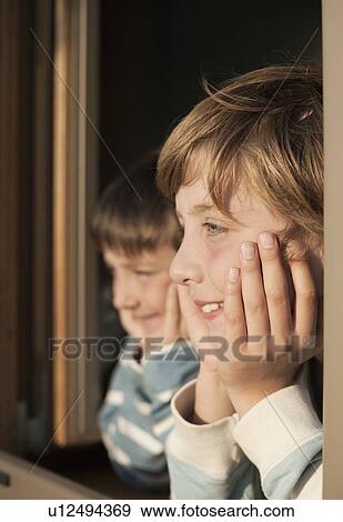Two boys looking out of window View Large Photo Image Stock Photo - Two boys looking out of window. Fotosearch