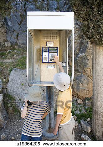 Stock Photography - Two boys on phone in public phone box. Fotosearch