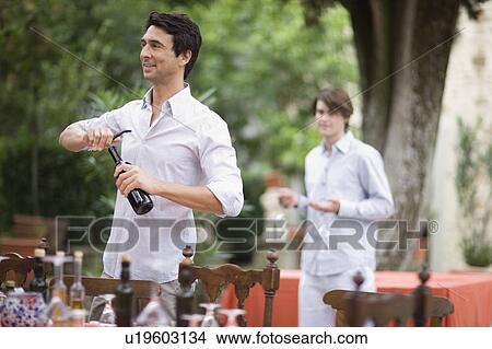 Picture - Two men preparing the table. Fotosearch