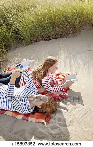 Two teenagers ready books in the dunes View Large Photo Image Stock Image - Two teenagers ready books in the dunes. Fotosearch