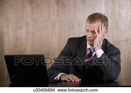 Picture - Unhappy business man looking at computer. Fotosearch