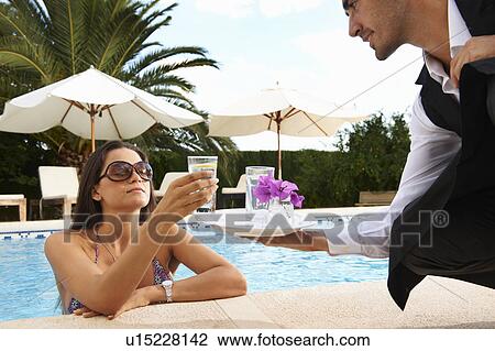 Stock Image - Waiter serving drinks to girl in pool. Fotosearch