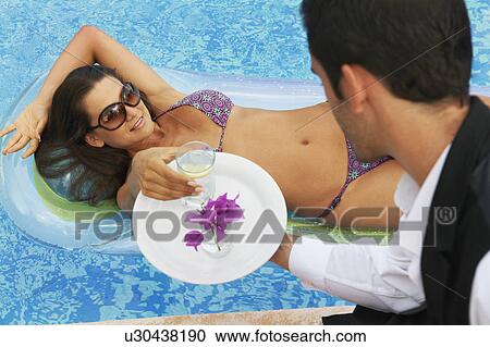 Stock Image - Waiter serving drinks to girl in pool. Fotosearch