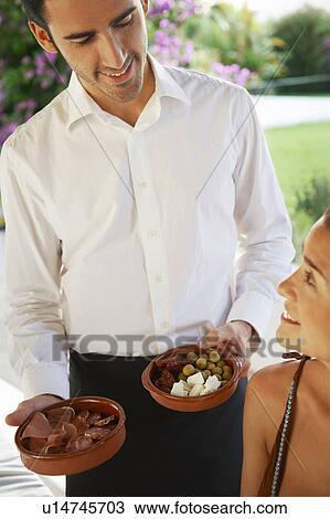 Stock Image - Waiter serving food to girl at a table. Fotosearch