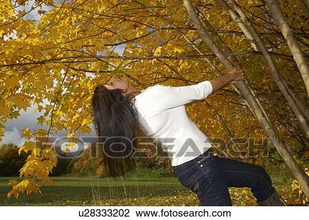 Stock Image - Womam pulling on tree in autumn. Fotosearch