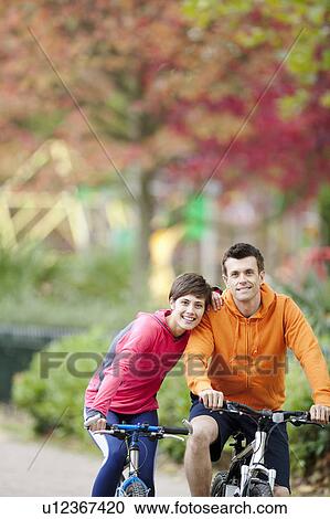 Woman and man cycling through the park View Large Photo Image Stock Image - Woman and man cycling through the park. Fotosearch