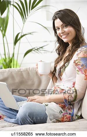 Stock Photography - Woman at home with hot drink online. Fotosearch