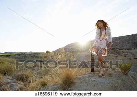 Stock Photo - Woman carrying guitar at sunset. Fotosearch