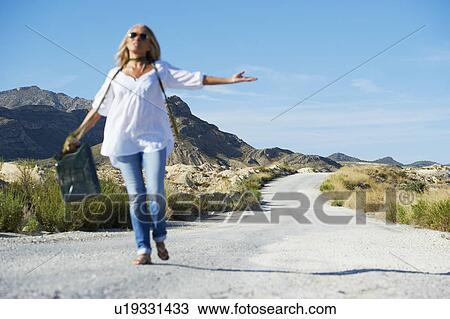 Stock Image - Woman carrying petrol can on the road. Fotosearch