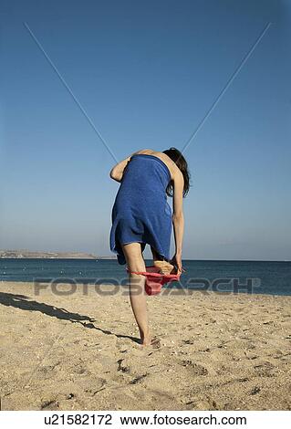 Stock Image - Woman changing out of bikini on beach. Fotosearch