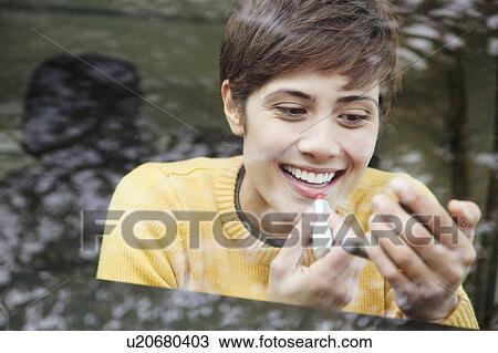Stock Image - Woman doing her make up in the car. Fotosearch
