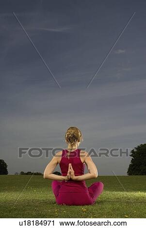 Stock Image - Woman doing yoga in park. Fotosearch