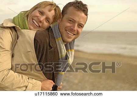 Woman embracing man from behind on beach View Large Photo Image Stock Image - Woman embracing man from behind on beach. Fotosearch