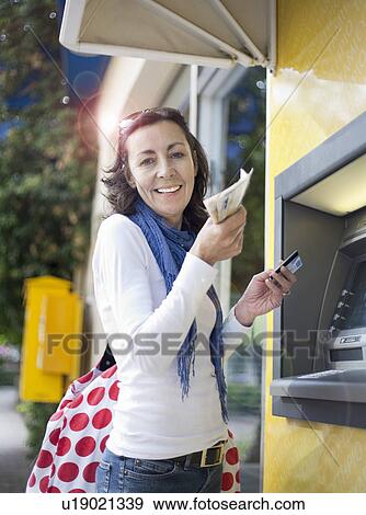 Stock Photo - Woman getting money from cash machine. Fotosearch