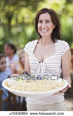 Picture - Woman holding a plate with pasta. Fotosearch