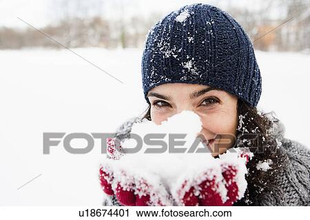 Stock Image - Woman holding snow in hands. Fotosearch
