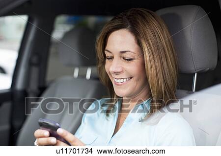 Woman in car checking cell phone View Large Photo Image Picture - Woman in car checking cell phone. Fotosearch