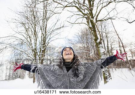 Stock Image - Woman in snowy woods embracing sky. Fotosearch