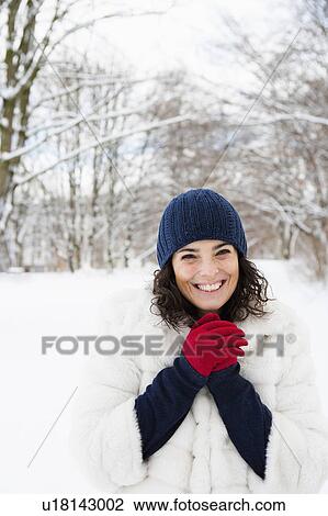 Stock Image - Woman in snowy woods rubbing her hands. Fotosearch