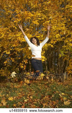 Woman jumping and throwing leaves View Large Photo Image Stock Photography - Woman jumping and throwing leaves. Fotosearch
