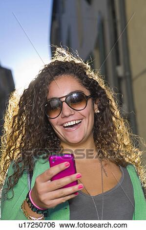 Stock Photograph - Woman laughs at cell phone in street. Fotosearch