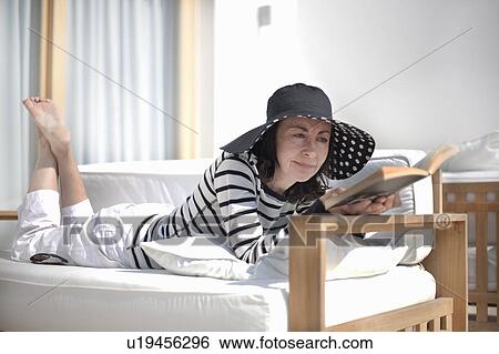 Woman lying on lounger, reading book View Large Photo Image Stock Photograph - Woman lying on lounger, reading book. Fotosearch