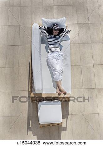 Stock Photo - Woman lying on outdoor sofa. Fotosearch