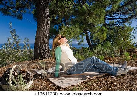 Stock Image - Woman on blanket relaxing in rural scene. Fotosearch