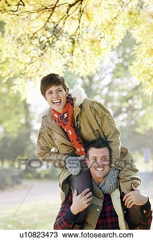 Woman on mans shoulders in the park View Large Photo Image Stock Image - Woman on mans shoulders in the park. Fotosearch