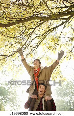 Woman on mans shoulders in the park View Large Photo Image Stock Image - Woman on mans shoulders in the park. Fotosearch