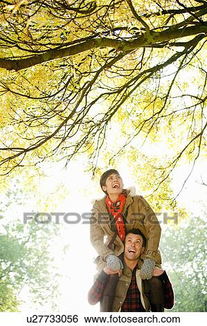 Woman on mans shoulders in the park View Large Photo Image Stock Photograph - Woman on mans shoulders in the park. Fotosearch