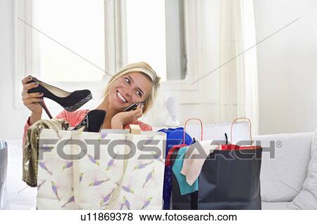 Woman on phone holds new shoes at home View Large Photo Image Stock Photo - Woman on phone holds new shoes at home. Fotosearch