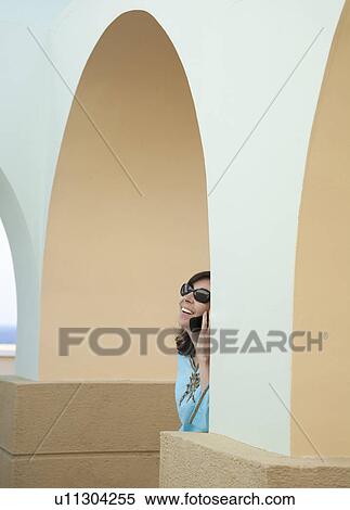 Stock Photography - Woman on phone under arches. Fotosearch